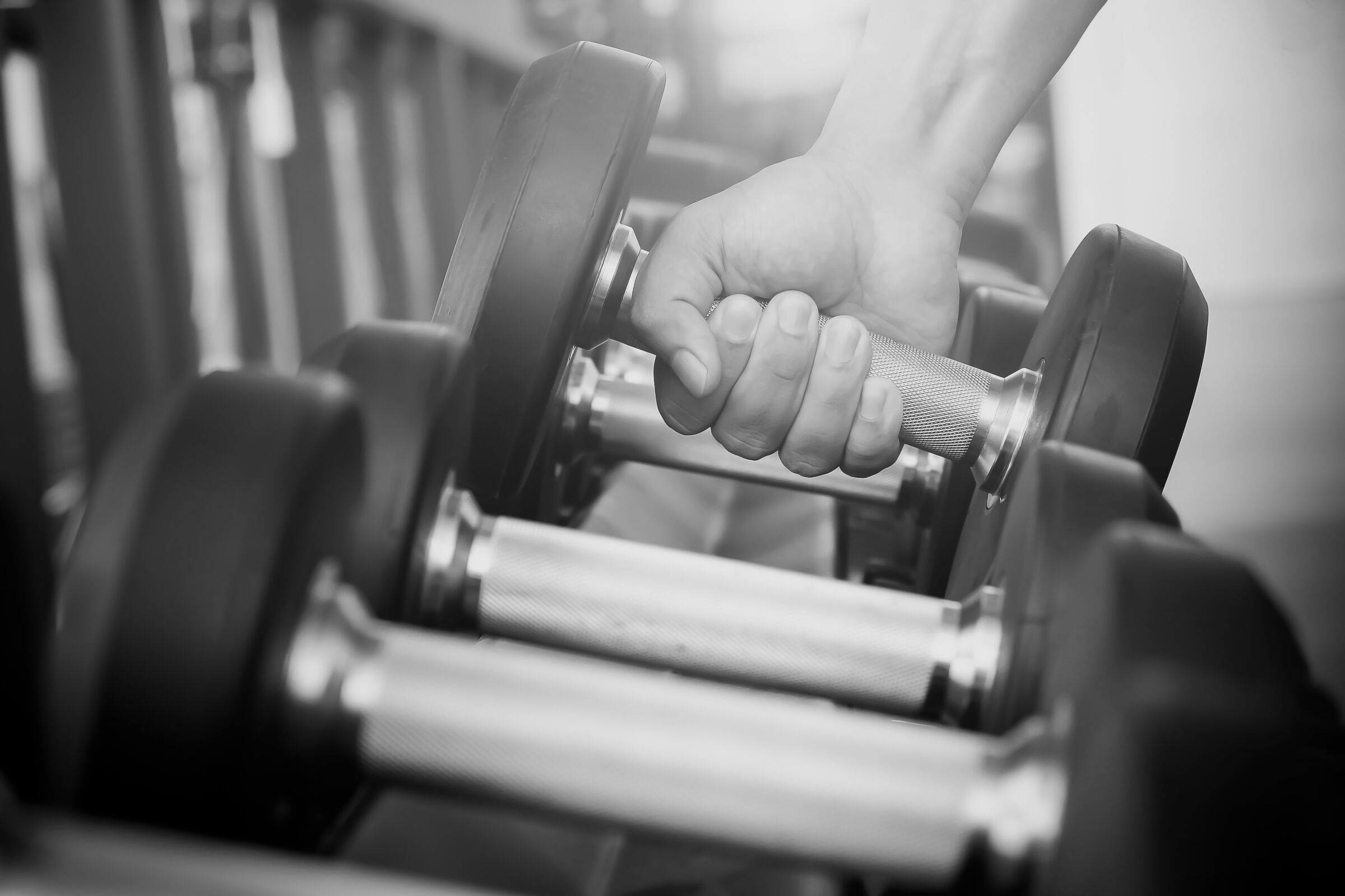 Hand Taking a Dumbbell from the Rack in the Gym